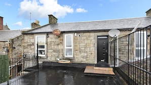 A stone building with a black door, a satellite dish, and a small window. - Troon Portland Apt A (Troon)