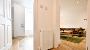 A modern, well-lit room with a wooden floor, a radiator, and a sofa set. - Troon Portland Apt A (Troon)