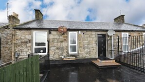 A stone building with a black roof, a satellite dish, and a gated entrance. - Troon Portland Apt B (Troon)