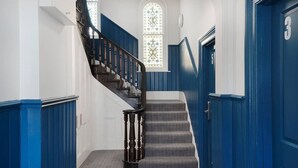 Eine Treppe mit blauen Wänden und einem Buntglasfenster.