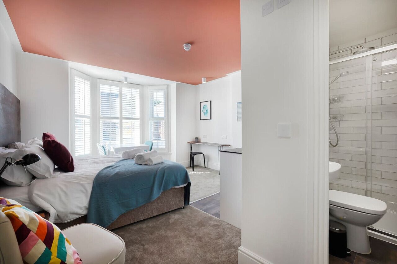 Een slaapkamer met een bed, een bureau en een badkamer met douche en toilet.