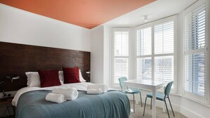 Ein Schlafzimmer mit einem großen Bett, einem Schreibtisch und einem Fenster mit Jalousien.
