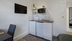 Uma cozinha compacta com televisão de tela plana, micro-ondas e pia.
