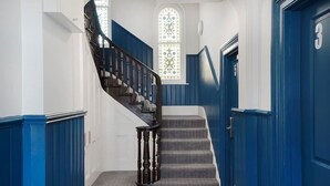 Uma escadaria com paredes azuis e uma janela de vitrais.