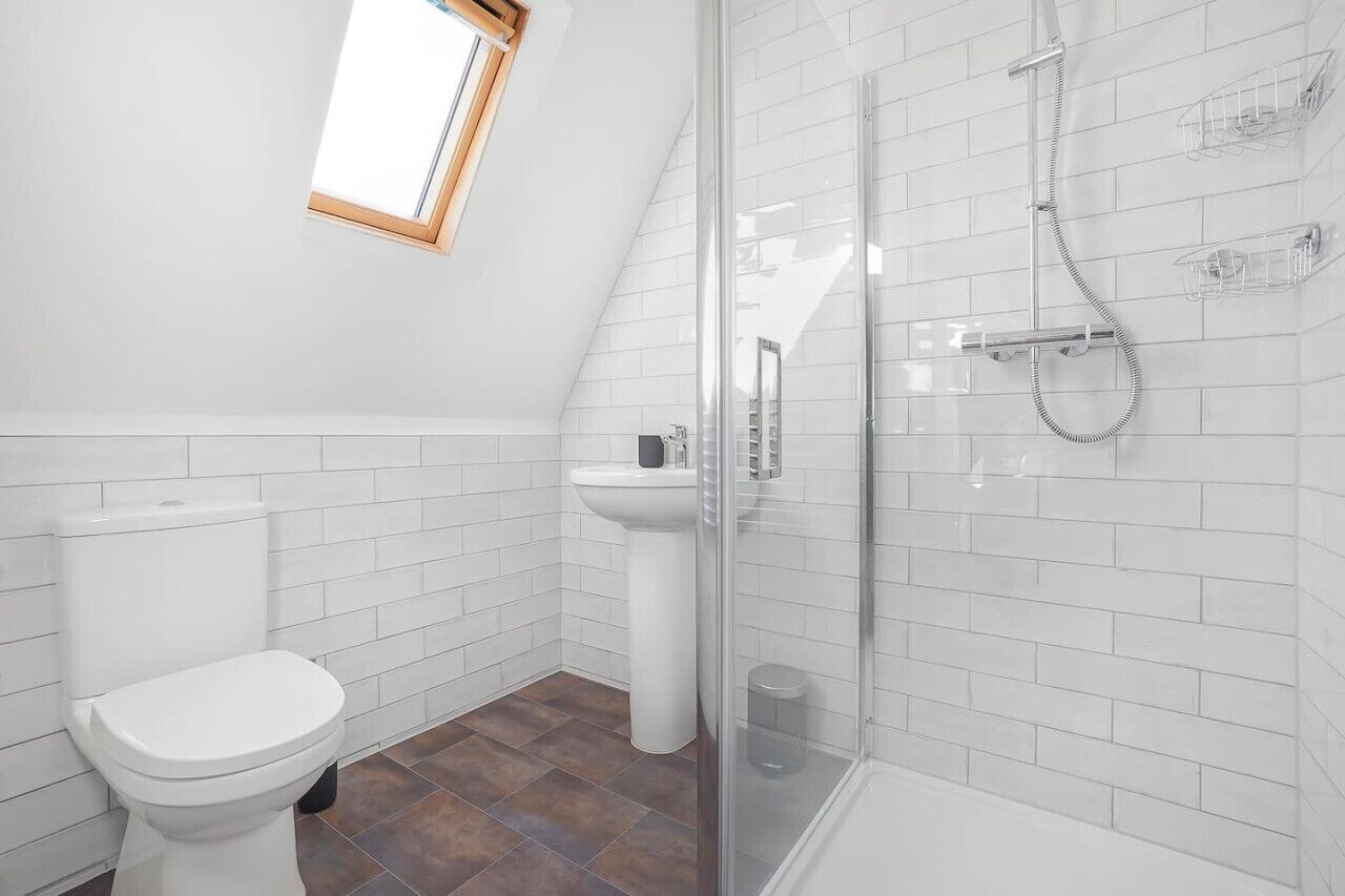 A modern bathroom with a toilet, sink, and glass-enclosed shower.