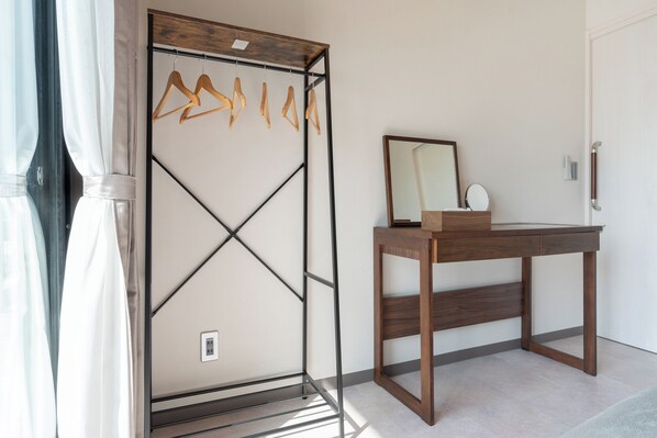A room with a wooden wardrobe, a mirror, and a table.