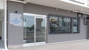 A modern building with a glass entrance, a sign reading "HOTEL AIRPORTVIEW NAHA," and a decorative metal gate.