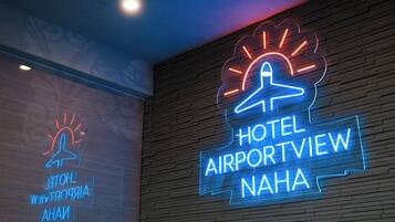 Ein Neon-Schild des Hotels HOTEL AIRPORTVIEW NAHA mit einem stilisierten Flugzeug- und Sonnendesign.