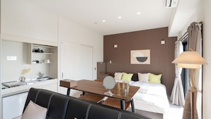 Une chambre d’hôtel moderne dotée d’une kitchenette, d’un coin repas, d’un lit avec un grand miroir et offrant une vue sur la ville.