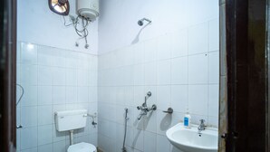 A small, basic bathroom with a toilet, a sink, and a shower. - Hotel Atithi Bhawan (Golmuri)