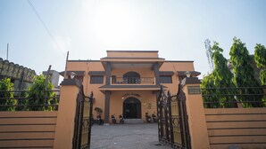 A hotel entrance with a gated driveway, a sign above the entrance, and a few parked motorcycles. - Hotel Atithi Bhawan (Golmuri)