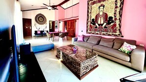 A spacious living room with a large sofa, a coffee table, and a dining area.