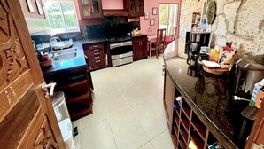 A kitchen with a central island, wooden cabinets, and a stone wall.