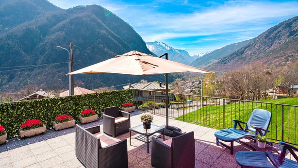 A terrace with outdoor furniture, a table, and a potted plant. - Alpine home with panoramic terrace and fireplace (Villaretto)