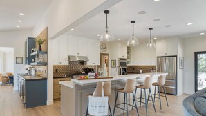 A modern kitchen with a central island, bar stools, and pendant lighting. - Private Paso Robles Vineyard Stay w Pool, Trails & Wine Views | Rancho de Robles (Paso Robles)