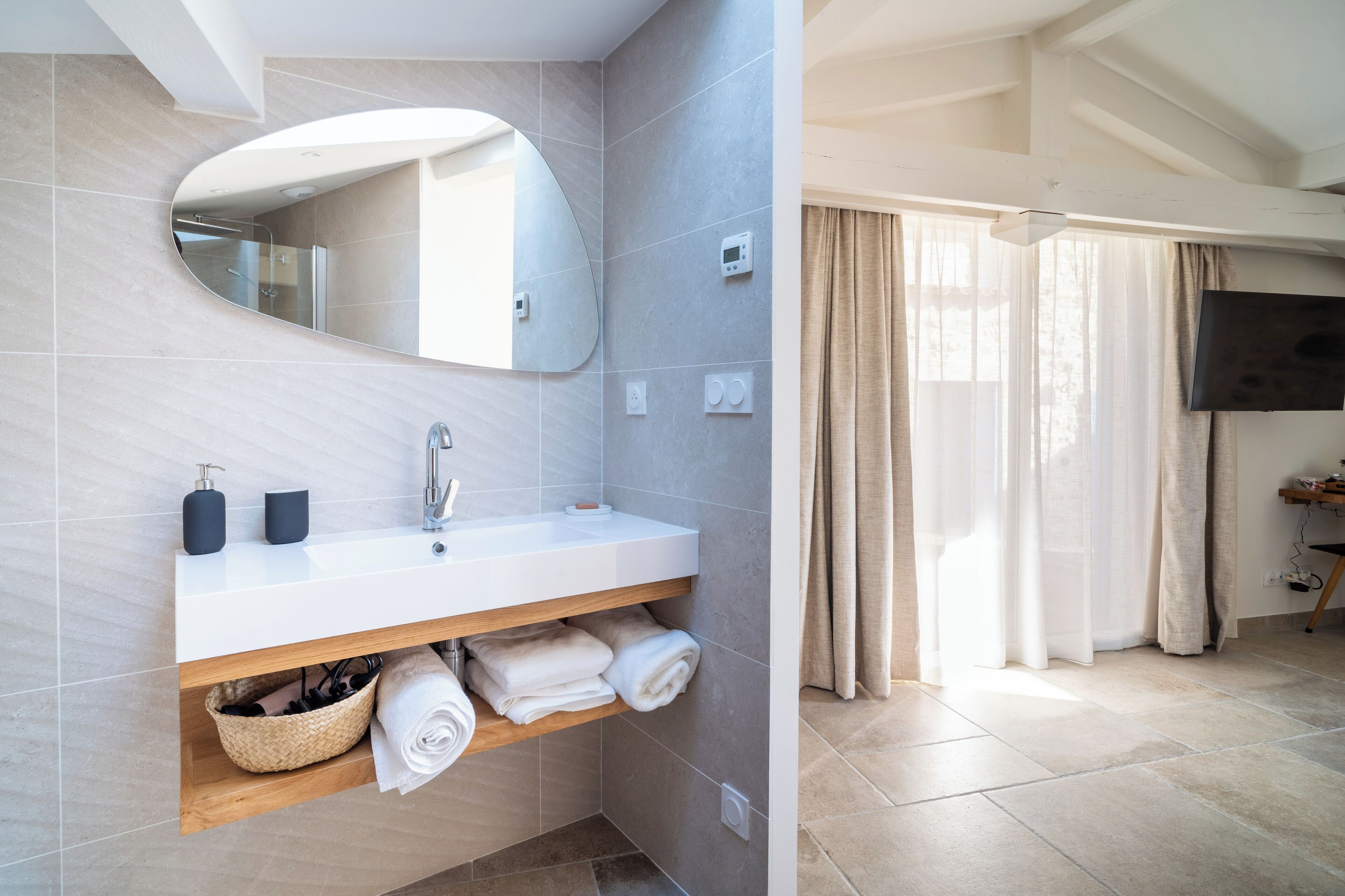 Een moderne badkamer met een witte wastafel, spiegel en handdoekenkast.