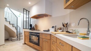 A modern kitchen with wooden cabinets, a stainless steel sink, and a built-in oven.