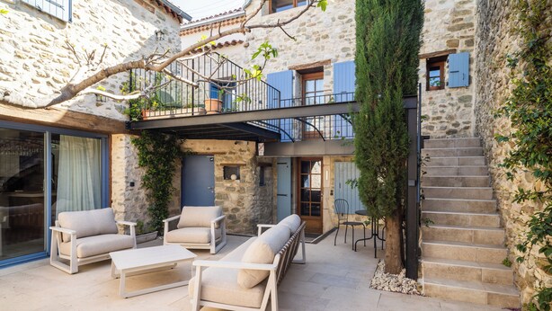 A stone building with a balcony, outdoor seating area, and a staircase.