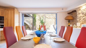 A dining area with a large table set for six, surrounded by red chairs. A blue bowl and wine glasses are on the table.