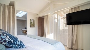 A bedroom with a bed, a TV, and a skylight.