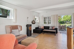Ein Wohnzimmer mit Kamin, Sofas und Blick ins Freie.