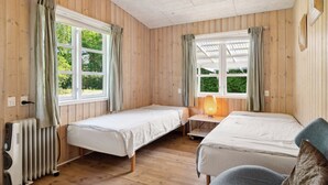A room with two beds, a heater, and a window with curtains. - Spacious summer house with pool. (Vejby)