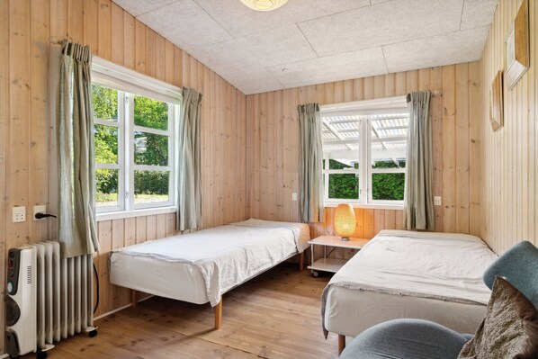 Ein Zimmer mit zwei Betten, einer Heizung und einem Fenster mit Vorhängen.
