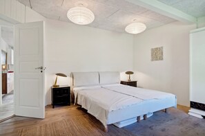 A bedroom with a bed, bedside tables, a door, and a ceiling light fixture. - Spacious summer house with pool (Vejby)