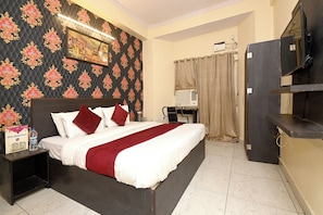 Una habitación de hotel con una cama grande, un escritorio y un televisor.