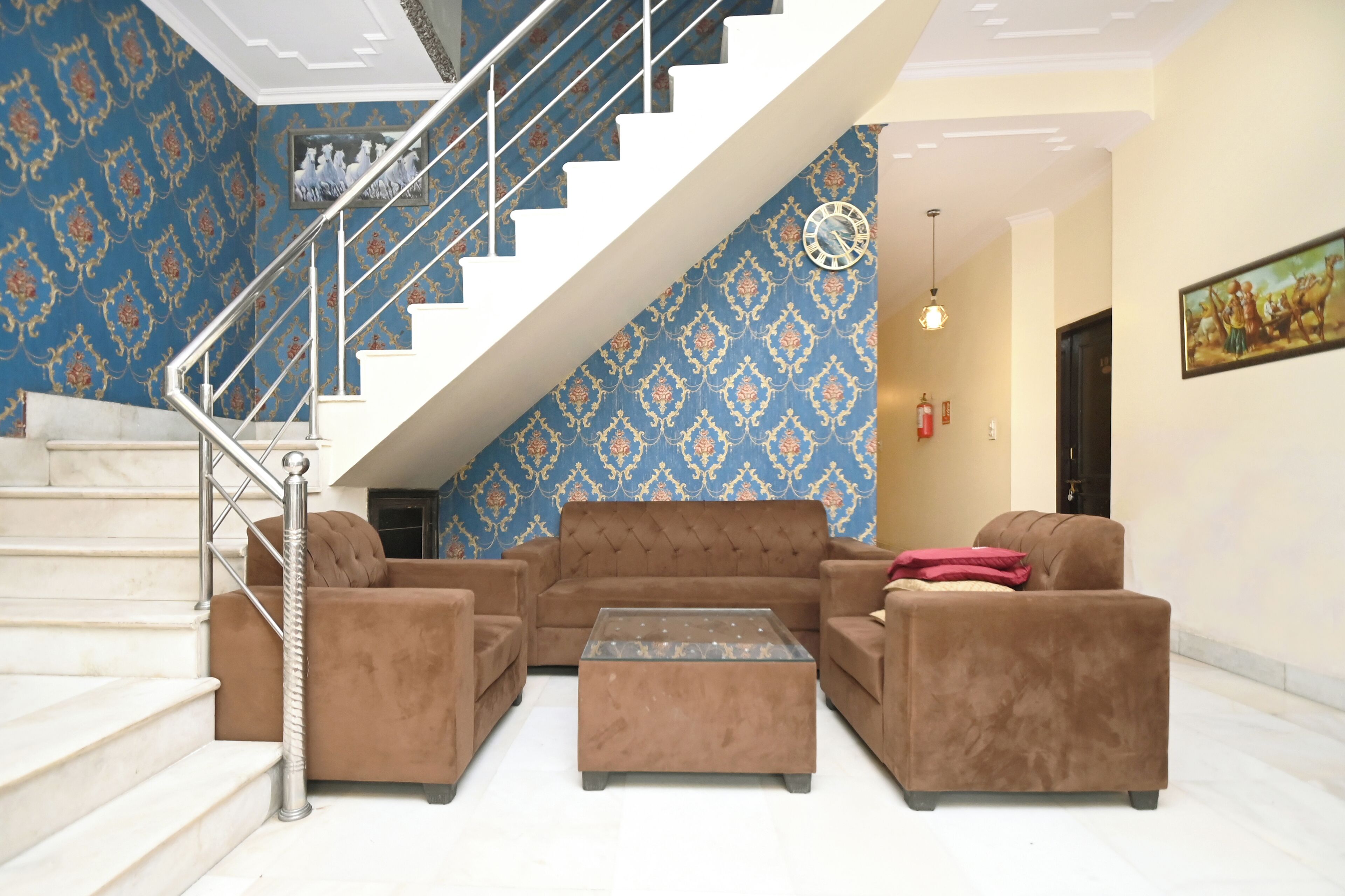 Ein Wohnzimmer mit Treppe, gemustertem Wandpapier und einer Sofagarnitur.