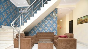 Una sala de estar con una escalera, papel tapiz estampado y un conjunto de sofás.