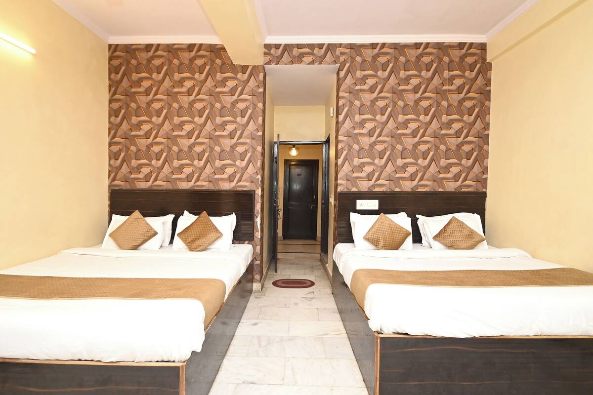 Una habitación de hotel con dos camas, un papel tapiz estampado y una puerta que da a otra habitación.
