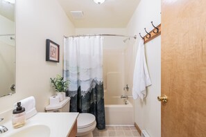 Ein Badezimmer mit Duschvorhang, Toilette, Waschbecken und Handtuchhalter.