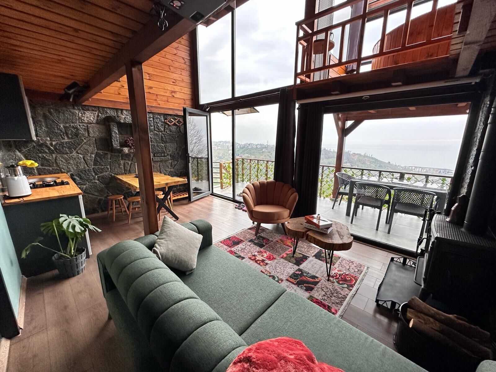 Un salón espacioso con un sofá verde, una mesa de comedor de madera y un balcón con vistas.