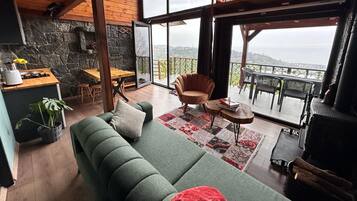 Un salón espacioso con un sofá verde, una mesa de comedor de madera y un balcón con vistas.