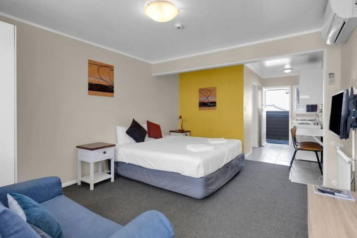 A hotel room with a bed, a desk, a TV, and a sofa.