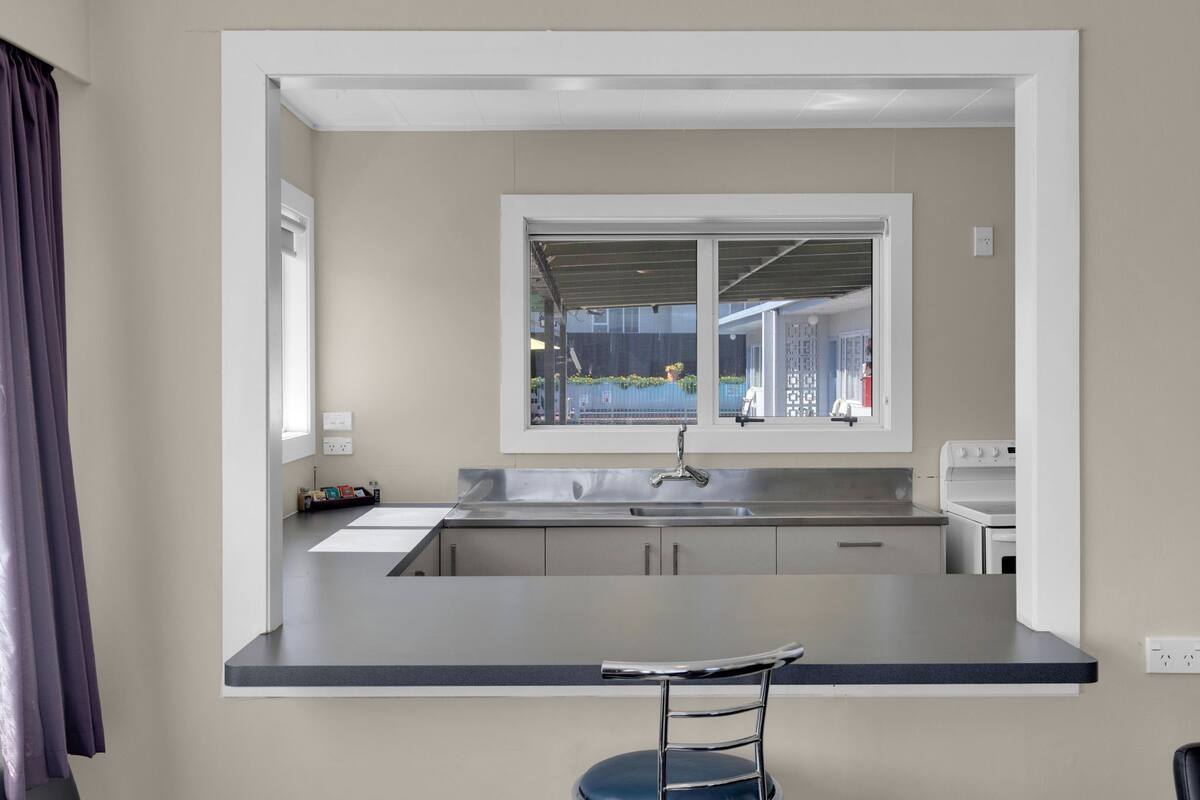 A modern kitchen with a bar counter, a window with a view of the outside, and a built-in oven.