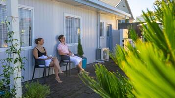 Two people seated on a porch with a house in the background.