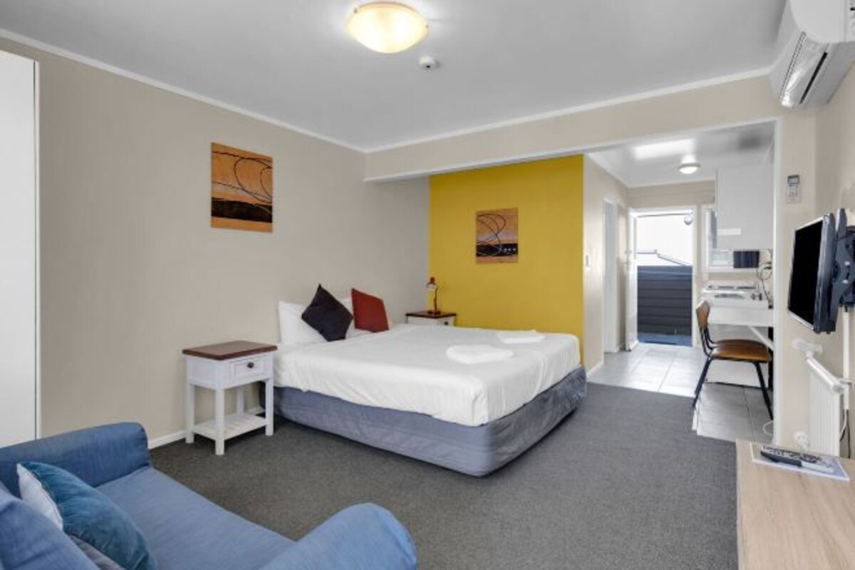 Une chambre d’hôtel avec un lit, un bureau, une télévision et un canapé.