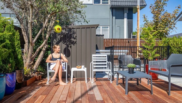 A wooden deck with outdoor furniture, a small table, and a potted plant. - Kowhai motel (Rotorua)