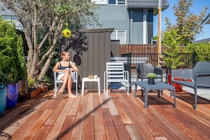 A wooden deck with outdoor furniture, a small table, and a potted plant. - Kowhai motel (Rotorua)