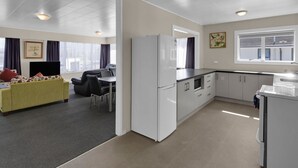 A compact living space with a kitchenette, a dining area, and a living room. - Kowhai motel (Rotorua)