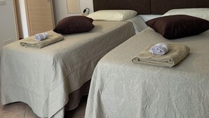 A hotel room with two beds, each with a rolled towel and pillows. There are three floral paintings on the wall. - Quadrifoglio affittacamere (Novi Ligure)