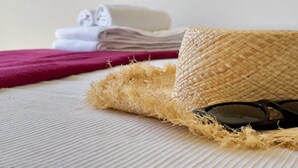 Ein Strohhut, Sonnenbrille und gefaltete Handtücher auf einem Bett.