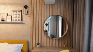 A modern bedroom with a bed, a desk, a chair, and a mirror.