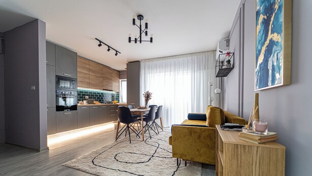 A modern kitchen with a dining area, a sofa, and a coffee table.