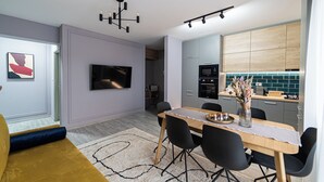 A modern living room with a TV, sofa, and dining area with chairs and a table.