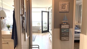 A hallway with a bench, a radiator, and a wall-mounted shelf with nautical-themed items.