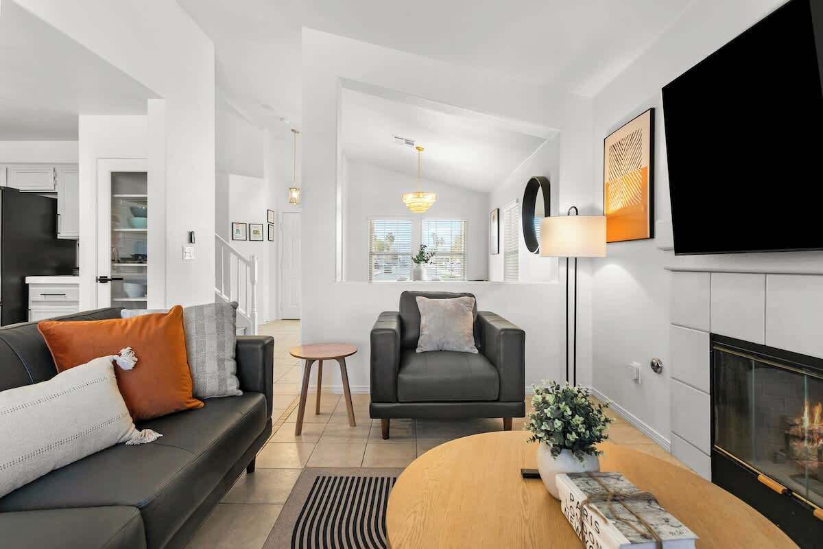 A modern living room with a sofa, armchair, coffee table, and fireplace.