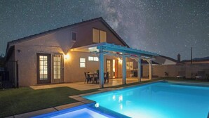 A house with a swimming pool, a covered patio, and a starry night sky. - 5BR Luxury Oasis w/ Pool & Spa + Games and MORE! (North Las Vegas)